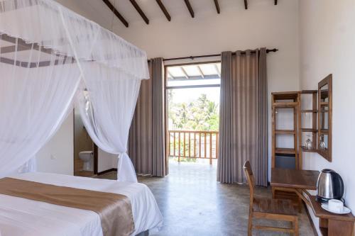 a bedroom with a bed and a desk and a window at Hotel Siyomin in Ahangama
