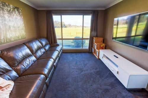 a living room with a leather couch and a large window at Chapman Hill Estate in Busselton