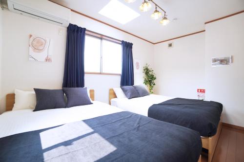 two beds in a room with a window at MATATABI STAY Tenroku w8 in Osaka