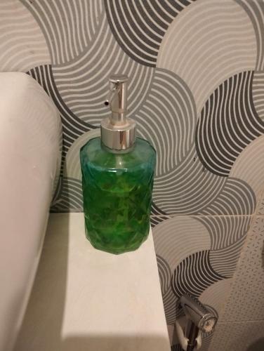 a green glass bottle sitting on a table in front of a wall at Two Brothers Guesthouse in Legian