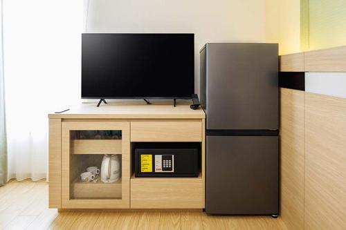 a flat screen tv on a stand with a refrigerator at HOTEL DREAM GATE maihama - Main & Annex in Urayasu