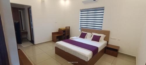 a bedroom with a bed with purple sheets and a window at Cardamom Vista Homestay in Thekkady