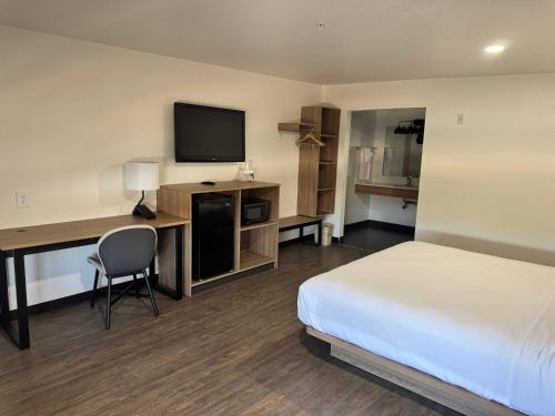 a hotel room with a bed and a desk with a television at Rodeway Inn & Suites Rancho Mirage - Palm Desert Area in Thousand Palms