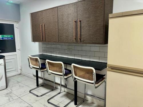 a kitchen with a counter with three chairs and a refrigerator at Family Room on Green road in Dudley