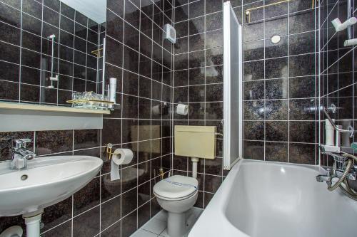 a bathroom with a sink and a toilet and a tub at Hotel Bavaria Trogir in Trogir