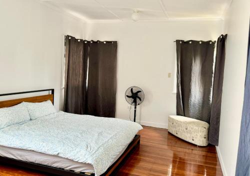 a bedroom with a bed and curtains and a wooden floor at Budget-Friendly Chermside Home Near Westfield in Brisbane