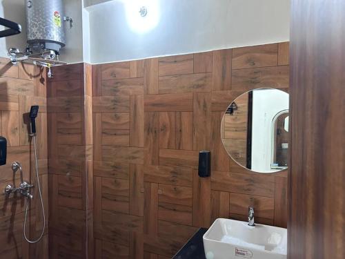 a bathroom with a wooden wall with a mirror and a sink at Abharam Retreats in Ghaziabad