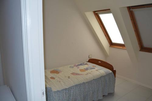 a small bed in a room with a window at Precioso ático a pie de playa, en Miño in Miño