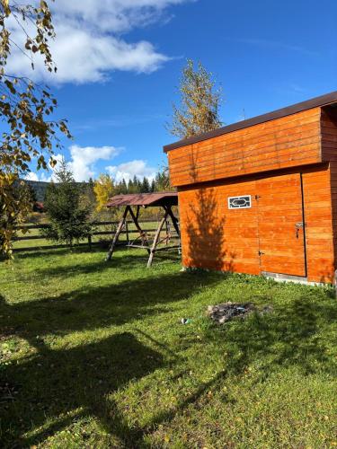 Un edificio de madera en un campo de hierba con cenizas. en Szakács Vendégház, en Borzont