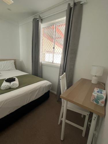 a bedroom with a bed and a table and a window at Double room with shared bathoom in Auburn