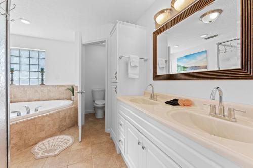 a bathroom with two sinks and a tub and a mirror at 308 Formosa Drive in Cocoa Beach