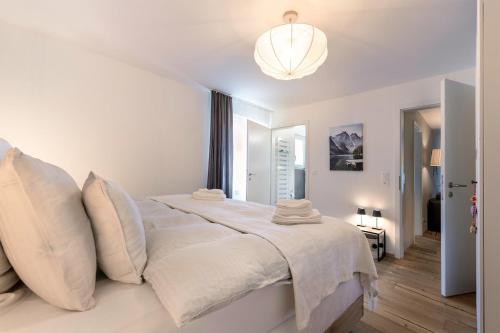 a white bedroom with a large bed and a chandelier at Alpine Lodge 63 in Andermatt