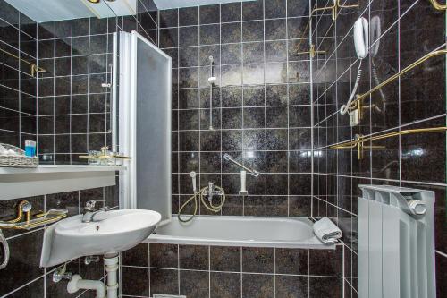 a black tiled bathroom with a sink and a tub at Hotel Bavaria Trogir in Trogir