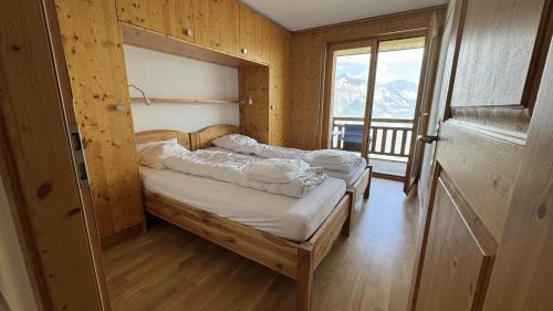 two beds in a wooden room with a window at Plein Ciel VA 031 - MOUNTAIN apartment 8 pers in Veysonnaz