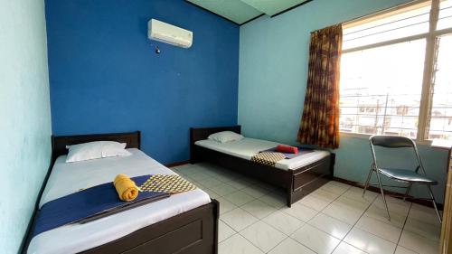 a room with two beds and a window and a chair at Hotel Budi Famili Budget Syariah in Ciamis