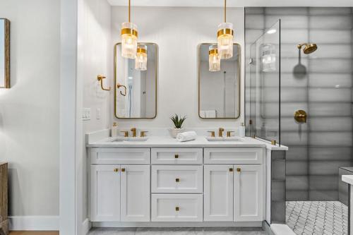 a white bathroom with two sinks and two mirrors at 30 8th Avenue in Indialantic