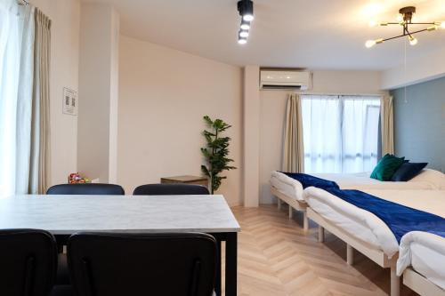 a room with two beds and a table and chairs at 梅田から1駅 - Umeda 1stop, Shin-Osaka 10m, 2m to Sta, 2F - XS41 in Osaka