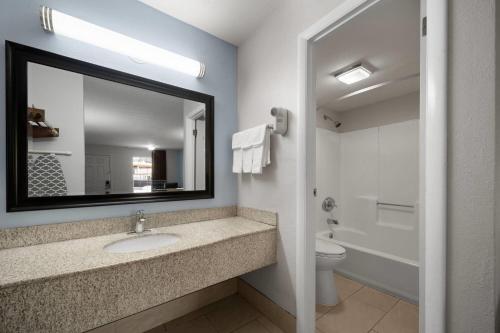 a bathroom with a sink and a toilet and a mirror at Super 8 by Wyndham Covington in Covington