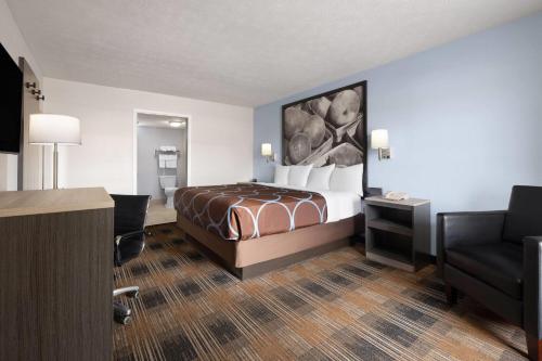 a hotel room with a bed and a chair at Super 8 by Wyndham Covington in Covington