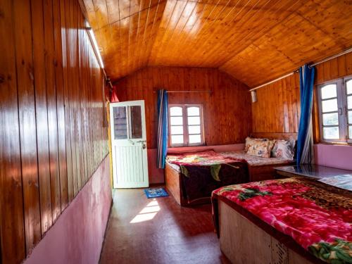 a room with two beds in a wooden cabin at Peshok Subba Homestay By StayApart in Darjeeling