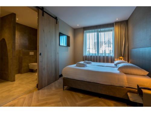 a bedroom with a large bed and a bathroom at Modern villa in De Cocksdorp near the beach in De Cocksdorp