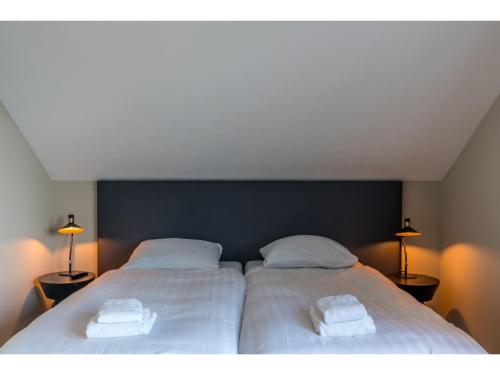 a bedroom with two beds with white sheets and towels at Modern villa in De Cocksdorp near the beach in De Cocksdorp