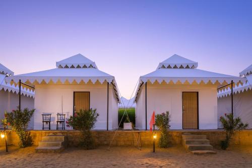 a group of white buildings with blue roofs at The Saffron Desert Camp, Jaisalmer in Jaisalmer