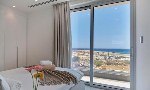 a bedroom with a bed and a large window with the ocean at Sea Pearl Seaview Villa - Oriana in Ayia Napa