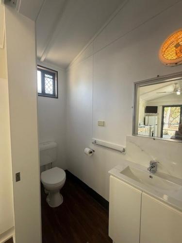 a white bathroom with a toilet and a sink at Kin Kora Village in Gladstone