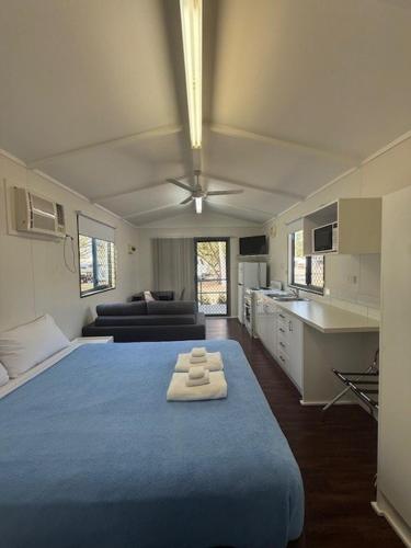 a room with a large blue bed and a kitchen at Kin Kora Village in Gladstone