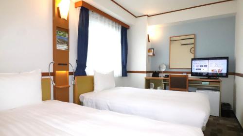 a hotel room with two beds and a desk with a computer at Toyoko Inn Tokyo Monzen-nakacho Eitaibashi in Tokyo