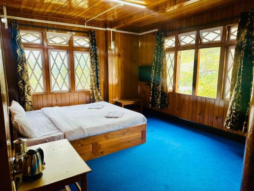 a bedroom with a bed and a table and windows at Cliff View Residency Lachung in Lachung