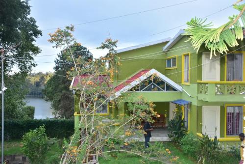 a woman standing in front of a green house at Mookambigai Residency in Kodaikānāl