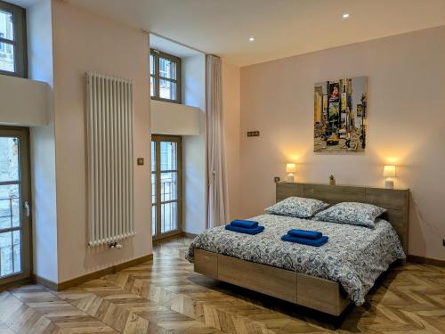 a bedroom with a bed with blue pillows on it at Gîte des Siècles - Maison du XIVe siècle avec Ascenseur et Cinéma in Saint-Gengoux-le-National