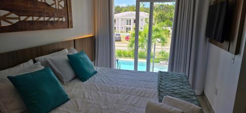 ポルト・セグロにあるParaíso com conforto em Arraial d'Ajuda - Casa 6 Gileadeの青い枕と窓のあるベッドのある寝室