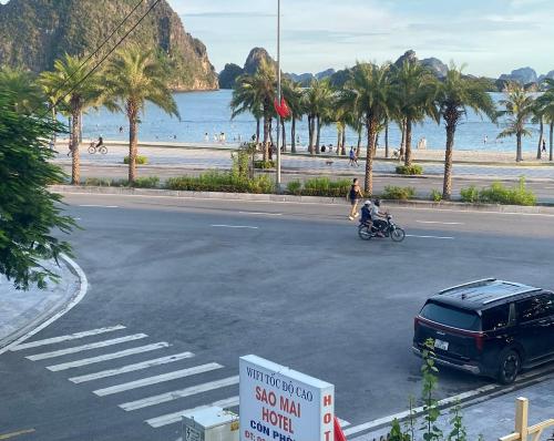 a street with a car and a person on a motorcycle at Sao Mai Hotel Hạ Long in Ha Long