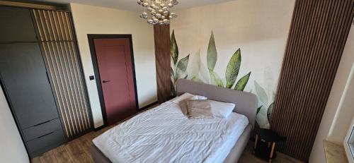 a bedroom with a bed with a plant on the wall at ZIBO APARTMENTS LESKO Nowoczesne apartamenty z jacuzzi i widokiem na Bieszczady in Lesko