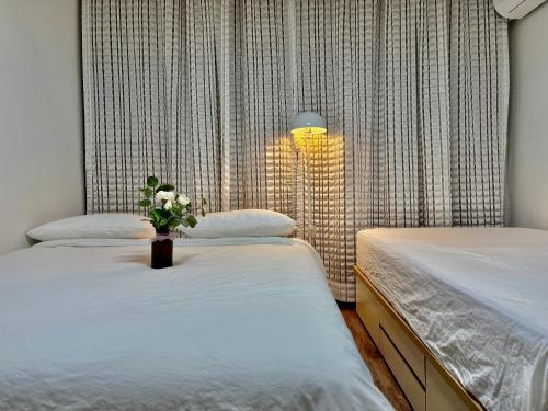 a bedroom with two beds and a vase of flowers at 루나스테이 in Seoul