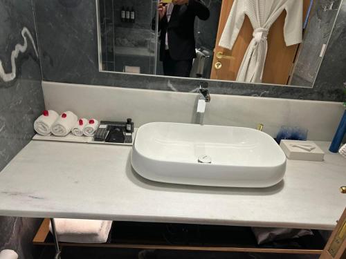 um lavatório branco numa casa de banho com uma pessoa a tirar uma fotografia em The Park New Delhi em Nova Deli