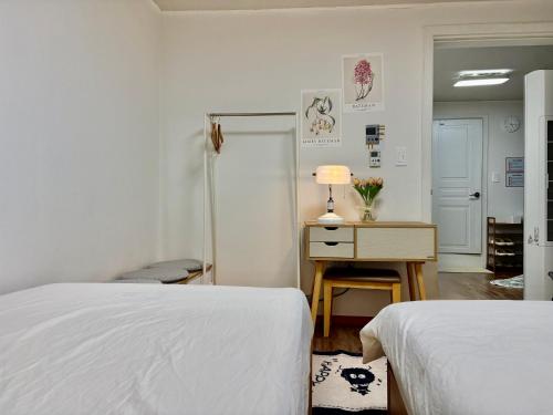 a bedroom with two beds and a desk with a lamp at Luna stay in Seoul