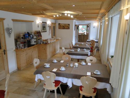 a dining room with tables and chairs and a kitchen at Garni Irsara in San Cassiano
