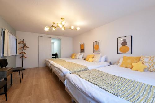 a room with three beds and a chandelier at 新大阪10分 - 1stop Umeda, Shin-Osaka 10m, USJ 30m, MAX6 - XS46 in Osaka