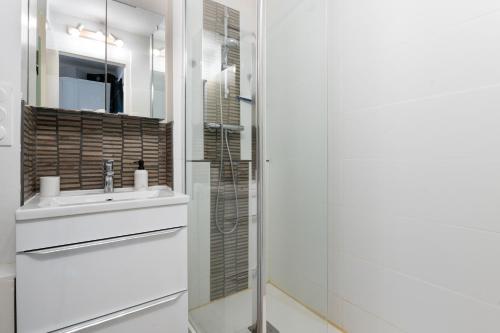 a white bathroom with a sink and a shower at L'Océanic vue mer, Draps et parking in Arzon