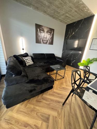 Una sala de estar con un sofá negro y una mesa. en Spa Apartament Wisła, en Wisła
