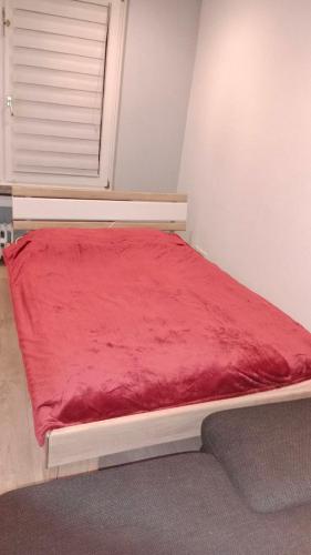 a bed with a red blanket on it in a room at Gemütliches Zimmer mit gemeinsamem WC in Oberhausen Osterfeld-Mitte in Oberhausen
