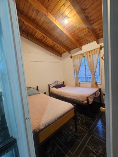 a room with two beds and a wooden ceiling at El Quisco cabaña con estacionamiento sector tranquilo in El Quisco