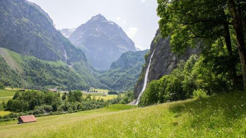a valley with a waterfall and a mountain at Berghaus Bergzyt - Apartment Älplersuite - im Ski und Wandergebiet in Linthal