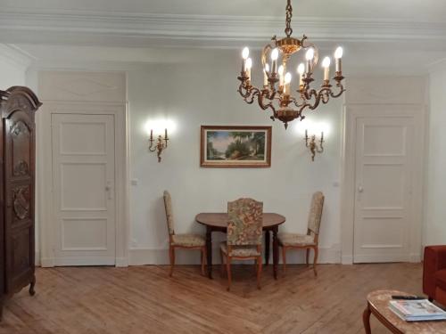 a dining room with a table and chairs and a chandelier at Le Royal in Bayeux