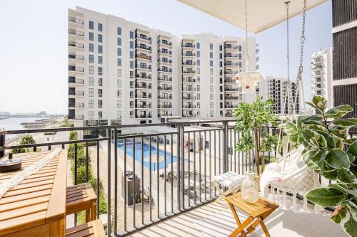 an apartment balcony with a pool and buildings at The Surfer's Yas 2BR plus Study Apartment, Full canal & pool view, Theme Parks Yas in Yas Island