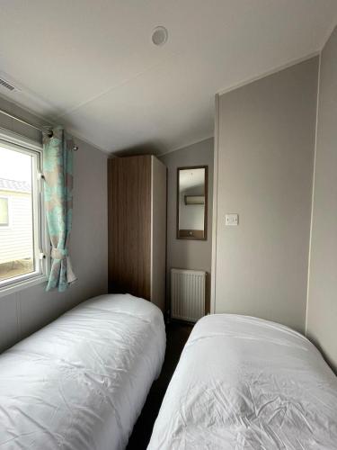 two beds in a small room with a window at 3 Bed Presthaven in Talacre